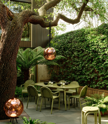 Tom Dixon Outdoor-Leuchten im stilvollen Garten mit Essbereich unter altem Baum.