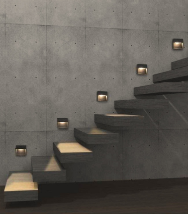 Dunkle quadratische Wandleuchten begleiten eine Betontreppe und beleuchten die Stufen.