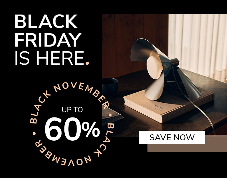 Save now A modern table lamp with angled metal blades sits on top of a book on a dark wooden desk in soft daylight. Text reads: ‘Black Friday is here. Up to 60%. Save Now.