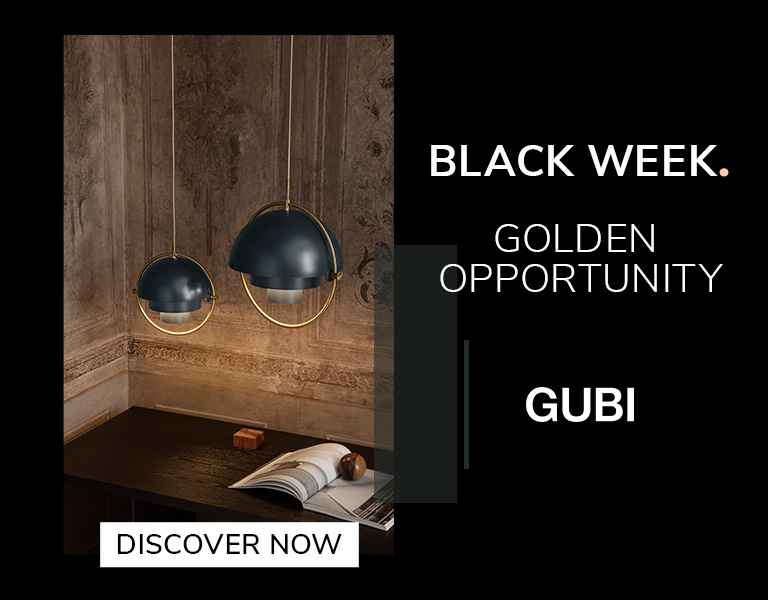 Discover more Two modern pendant lamps with dark blue domes and gold accents hanging above a wooden desk in a warmly lit, ornate room. Text reads: ‘Black Week. Golden Opportunity. GUBI.’ A button says ‘Discover Now.
